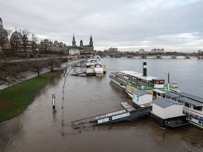 Ein Mann fährt mit seinem Fahrrad über die vom Hochwasser überfluteten Elbwiesen am Königsufer in Dresden. - Foto: Robert Michael/dpa