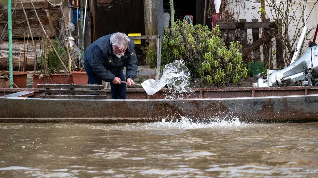 Ein Anwohner an der Fischerei in Bamberg schöpft Wasser aus einem Boot. - Bild: Pia Bayer/dpa