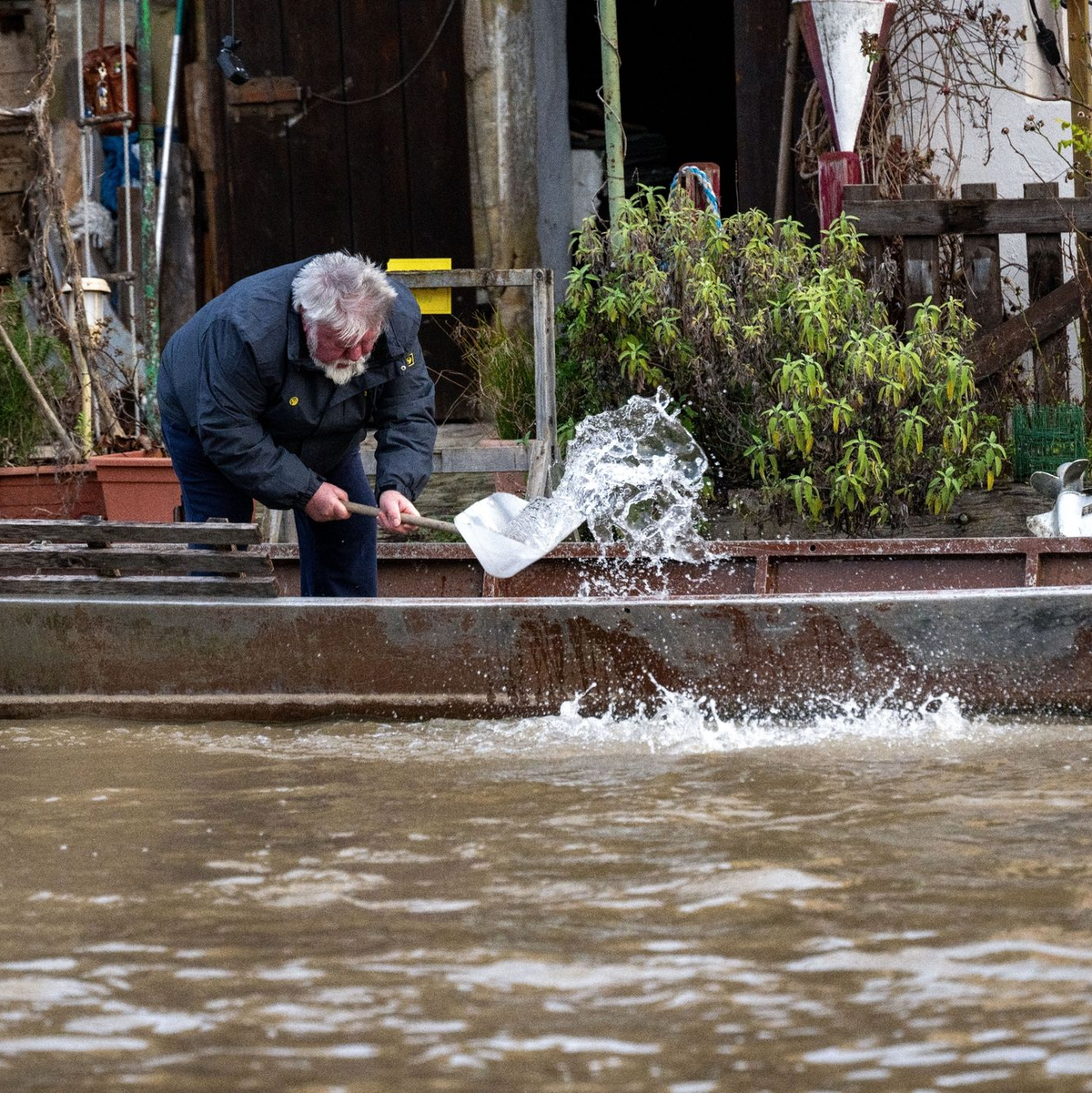 Ein Anwohner an der Fischerei in Bamberg schöpft Wasser aus einem Boot. - Foto: Pia Bayer/dpa
