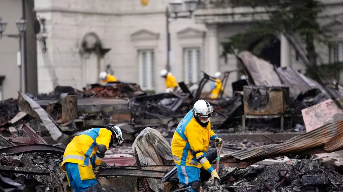 Polizeibeamte suchen nordwestlich von Tokio nach Opfern eines durch das Erdbeben verursachten Brandes. - Bild: Hiro Komae/AP