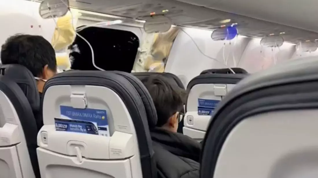 Passagiere sitzen in der Boeing 737-9 Max in der Nähe des abgerissenen Kabinenteils. - Bild: Elizabeth Le/Elizabeth Le/AP