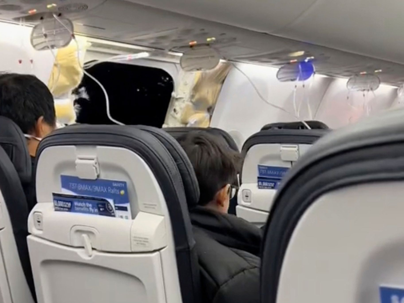 Passagiere sitzen in der Boeing 737-9 Max in der Nähe des abgerissenen Kabinenteils. - Foto: Elizabeth Le/Elizabeth Le/AP