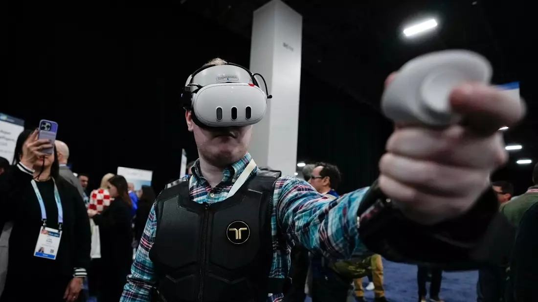 Ein Besucher probiert auf der CES die haptische Weste von bHaptics. Die Weste soll in Verbindung mit Augmented-Reality-Systemen verwendet werden, um haptisches Feedback in Videospielen zu geben. - Bild: Ryan Sun/AP/dpa