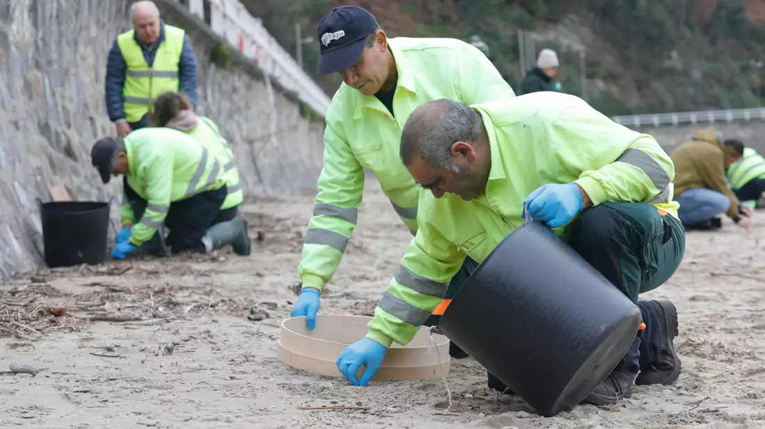 In mühsamer Handarbeit werden die Plastikkügelchen aufgesammelt. - Bild: Jorge Peteiro/EUROPA PRESS/dpa