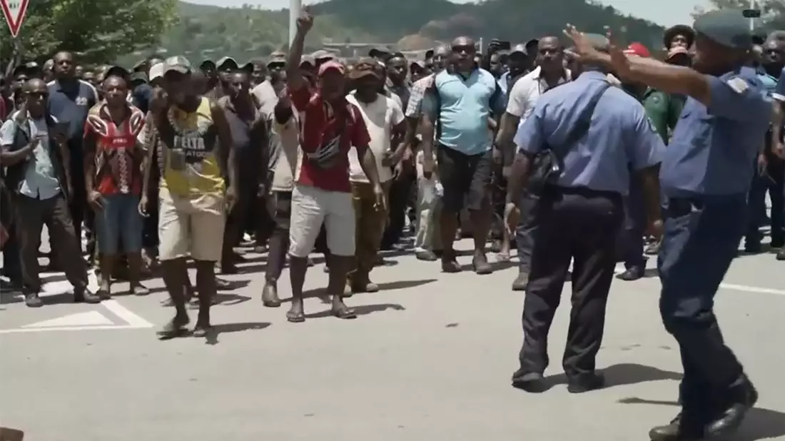 Das Videostandbild zeigt zwei Polizisten neben einer aufgebrachten Menschenmenge in Port Moresby. - Bild: Uncredited/Australian Broadcasting Corp/AP/dpa