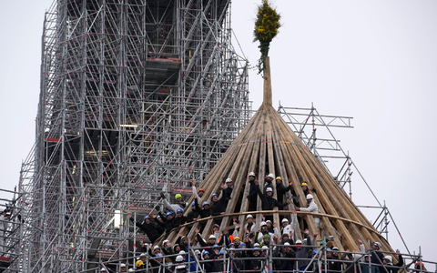 Arbeiter feiern den Abschluss des Wiederaufbaus des Dachstuhls der Kathedrale Notre Dame mit einem traditionellen Blumenstrauß. - Foto: Christophe Ena/AP/dpa