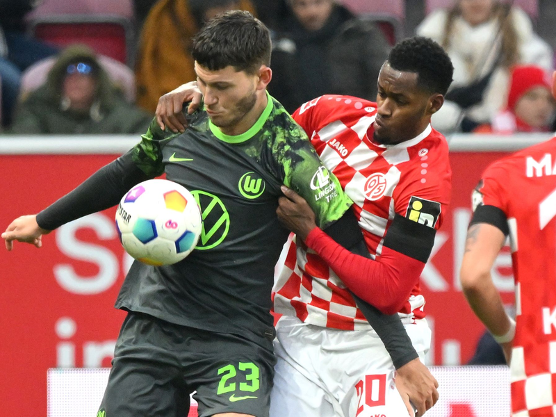 Wolfsburgs Jonas Wind (l) schirmt den Ball vor dem Mainzer Edmilson Fernandes ab. - Foto: Torsten Silz/dpa