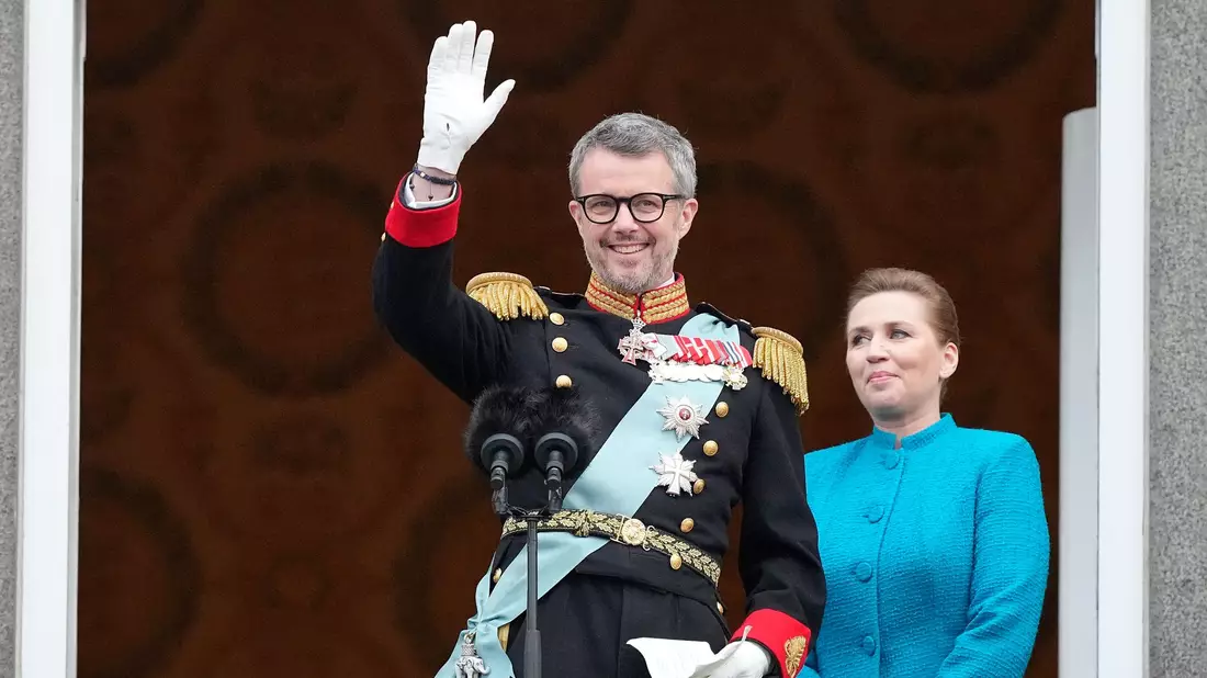 König Frederik X. von Dänemark winkt vom Balkon des Schlosses Christiansborg, während die dänische Ministerpräsidentin Mette Frederiksen zusieht. - Bild: Martin Meissner/AP