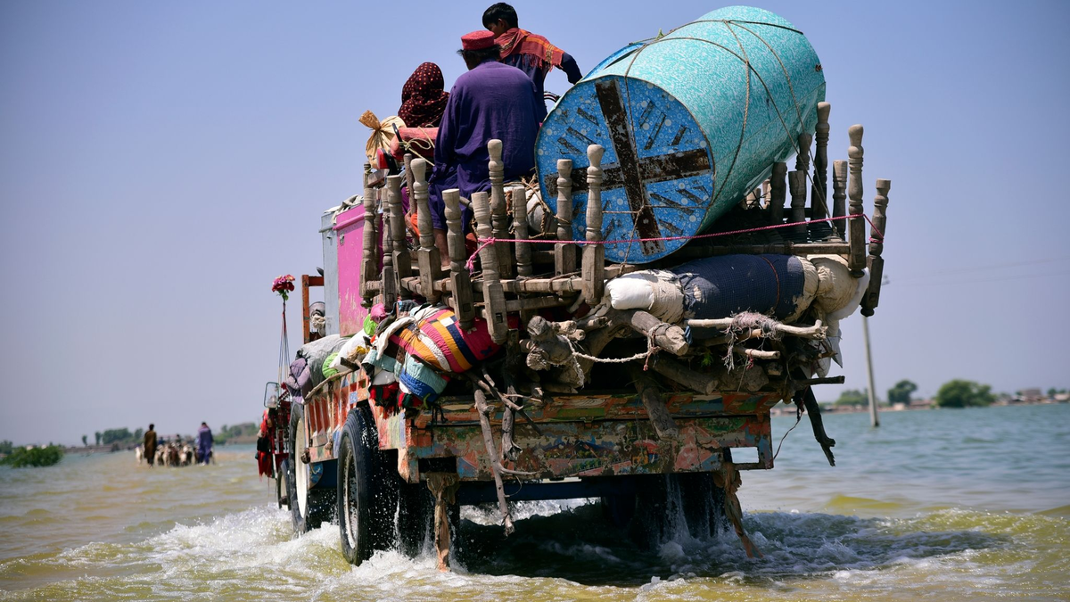 Opfer von Überschwemmungen durch Monsunregen tragen Habseligkeiten aus ihrem überfluteten Haus in der pakistanischen Provinz Sindh (Archivbild). Allein Überschwemmungen könnten Schätzungen zufolge bis 2050 für 8,5 Millionen Tote sorgen. - Foto: Pervez Masih/AP/dpa