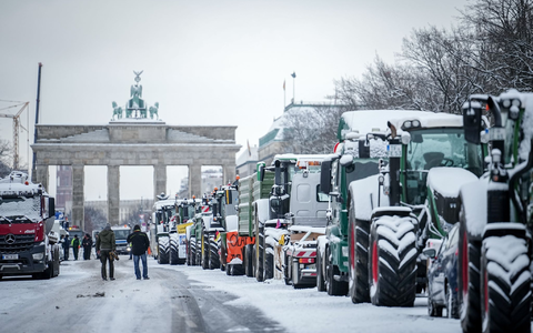 Zahlreiche schneebedeckte Traktoren stehen auf der Straße des 17. Juni vor dem Brandenburger Tor in Berlin. - Foto: Kay Nietfeld/dpa