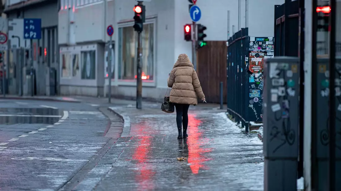 Achtung, glatt: Eine Fußgängerin passiert in Saarbrücken einen Gehweg, der sich nach Blitzeis in eine Rutschbahn verwandelt hat. - Bild: Laszlo Pinter/dpa