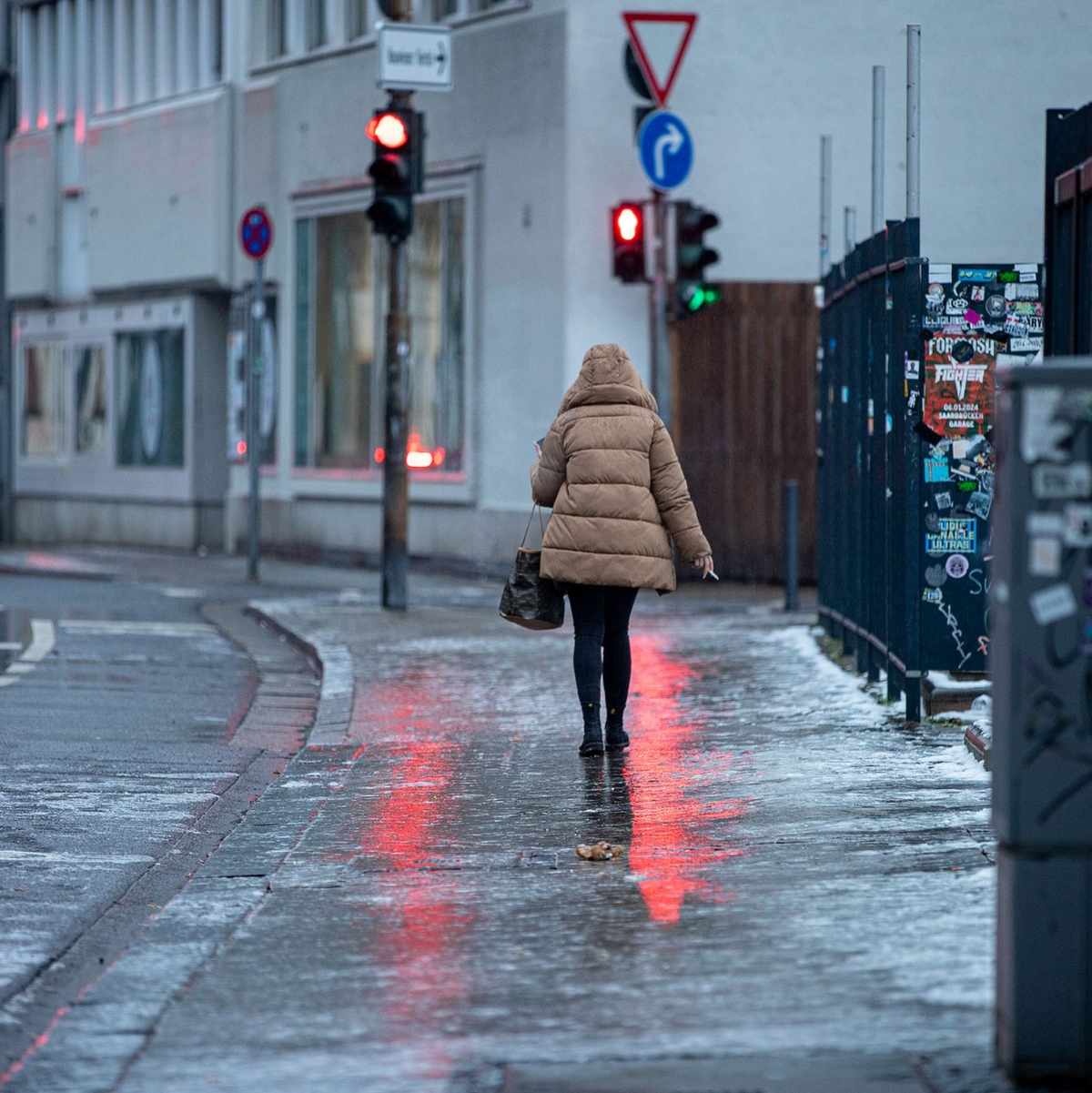 Achtung, glatt: Eine Fußgängerin passiert in Saarbrücken einen Gehweg, der sich nach Blitzeis in eine Rutschbahn verwandelt hat. - Foto: Laszlo Pinter/dpa