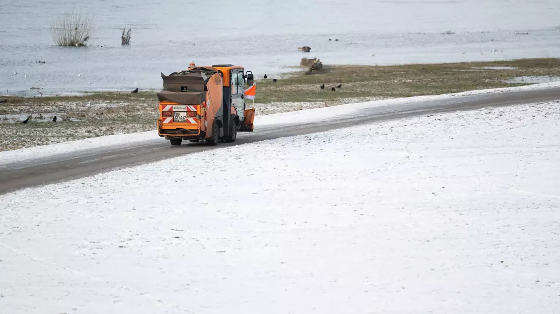 Ein Winterdienst-Fahrzeug fährt am Vormittag an den verschneiten Elbwiesen auf dem Radweg in Dresden entlang. - Bild: Robert Michael/dpa