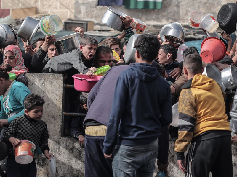 Palästinenser warten an einer Spendenstelle in einem Flüchtlingslager im südlichen Gazastreifen auf Lebensmittel. - Foto: Bashar Taleb/APA/ZUMA/dpa