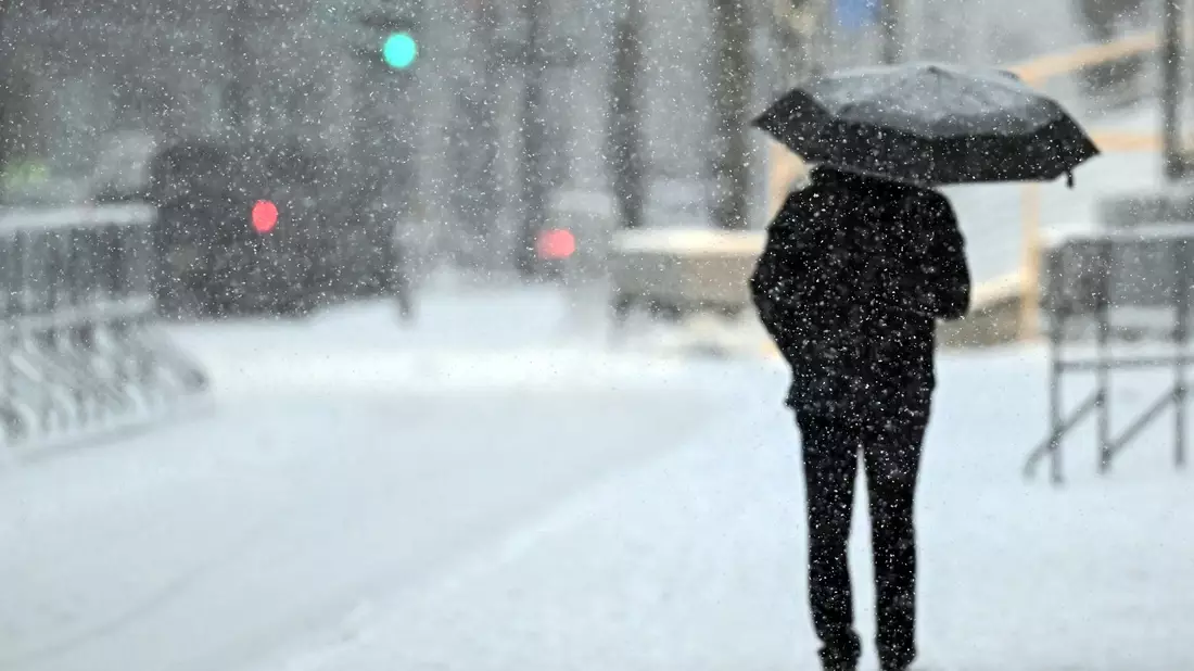 Ein Fußgänger geht mit einem Schirm durch das Schneetreiben in Köln. - Bild: Federico Gambarini/dpa