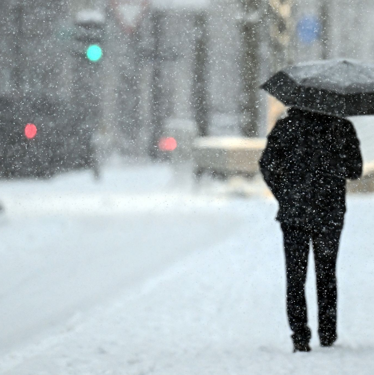 Ein Fußgänger geht mit einem Schirm durch das Schneetreiben in Köln. - Foto: Federico Gambarini/dpa