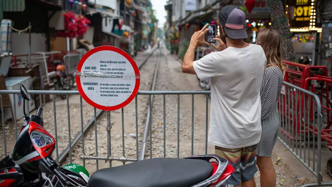 Zwei Touristen aus Brasilien fotografieren die abgesperrte «Train Street» in Hanoi. - Bild: Chris Humphrey/dpa
