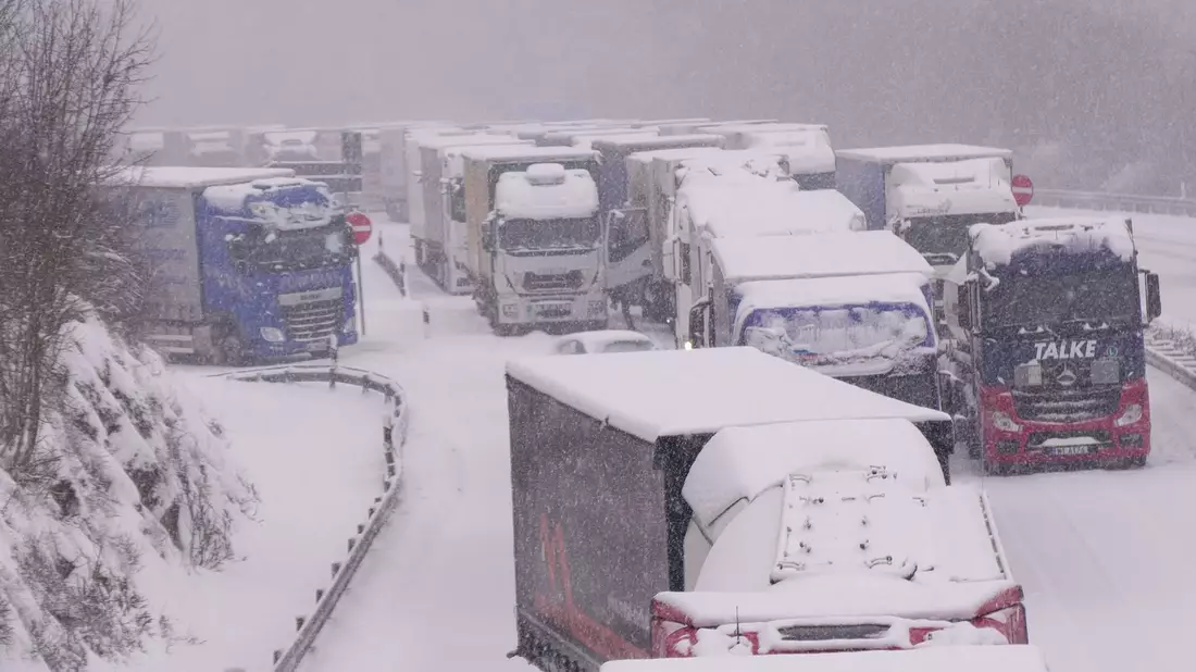 Lastwagen stecken im Stau auf der schneebedeckten Autobahn 5 bei Alsfeld fest. - Bild: Bernd März/dpa