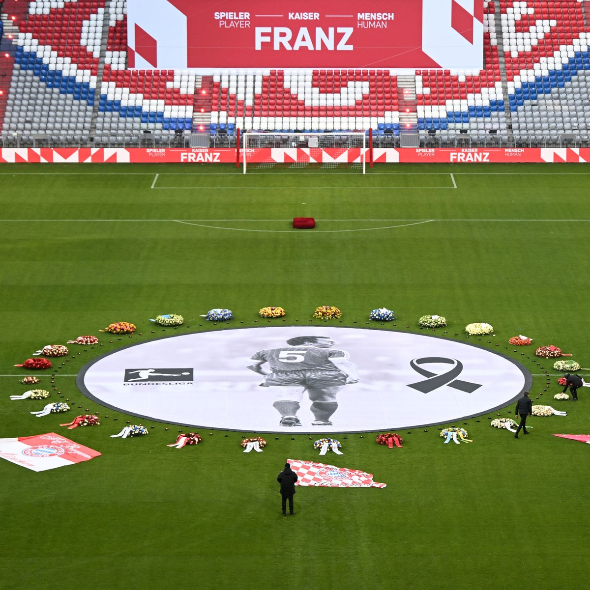 Fahnen von FCB-Fanclubs liegen neben einem überlebensgroßen Beckenbauer-Bild im Mittelkreis der Allianz Arena. - Foto: Sven Hoppe/dpa