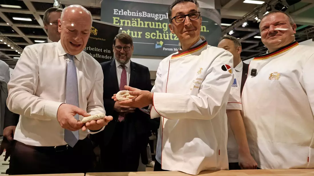 Bundesagrarminister Cem Özdemir und Berlins Regierender Bürgermeister Kai Wegner formen Brezeln beim Eröffnungsrundgang über das Messegelände der Grünen Woche. - Bild: Carsten Koall/dpa