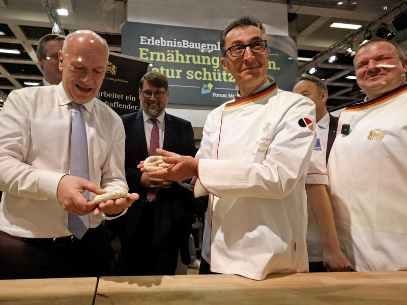 Bundesagrarminister Cem Özdemir und Berlins Regierender Bürgermeister Kai Wegner formen Brezeln beim Eröffnungsrundgang über das Messegelände der Grünen Woche. - Foto: Carsten Koall/dpa