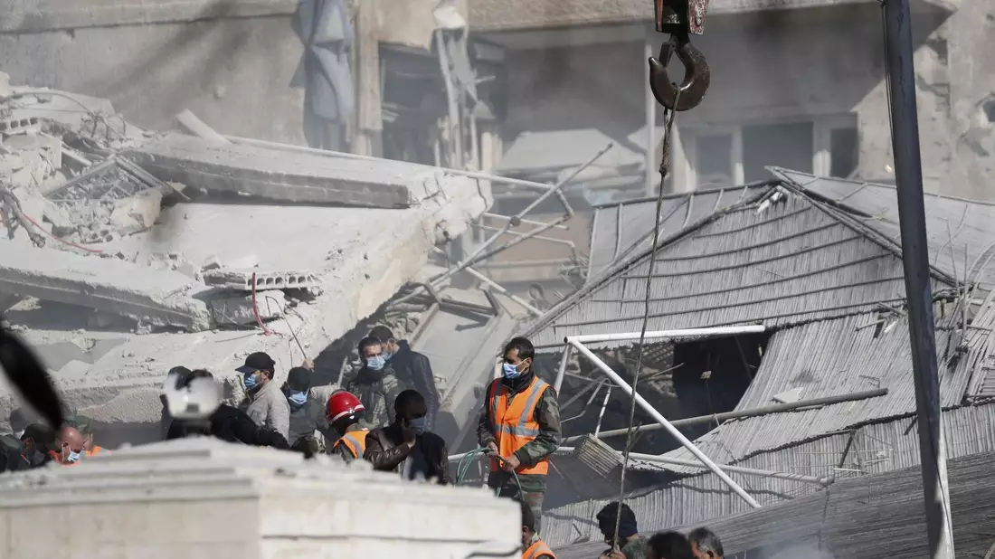 Rettungskräfte stehen in Damaskus an dem durch den Luftangriff zerstörten Gebäude. - Bild: Omar Sanadiki/AP/dpa