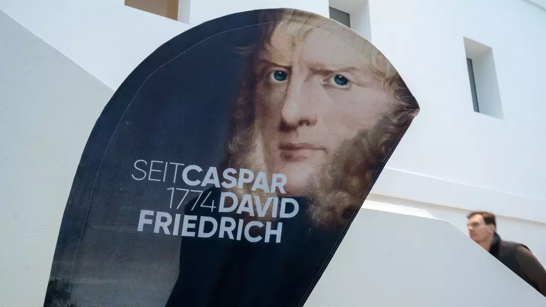 Ein Aufsteller mit einem Porträtbild von Caspar David Friedrich steht im Greifswalder Landesmuseum. - Bild: Stefan Sauer/dpa