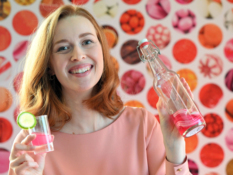 Model Christin hält auf der Internationalen Süßwarenmesse ein Glas Wodka in der Hand, das mit Sweet Shots-Bonbonmasse versetzt wurde. - Foto: Federico Gambarini/dpa
