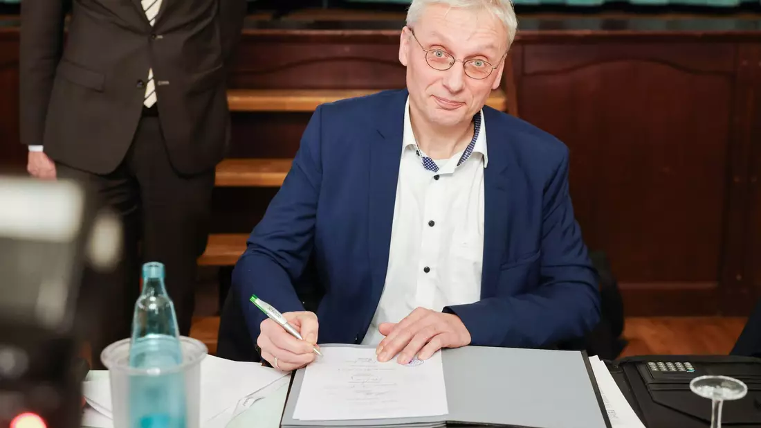 Kai Uwe Evers, der Bürgermeister von Norderwöhrden, unterzeichnet einen Durchführungsvertrag. - Bild: Christian Charisius/dpa