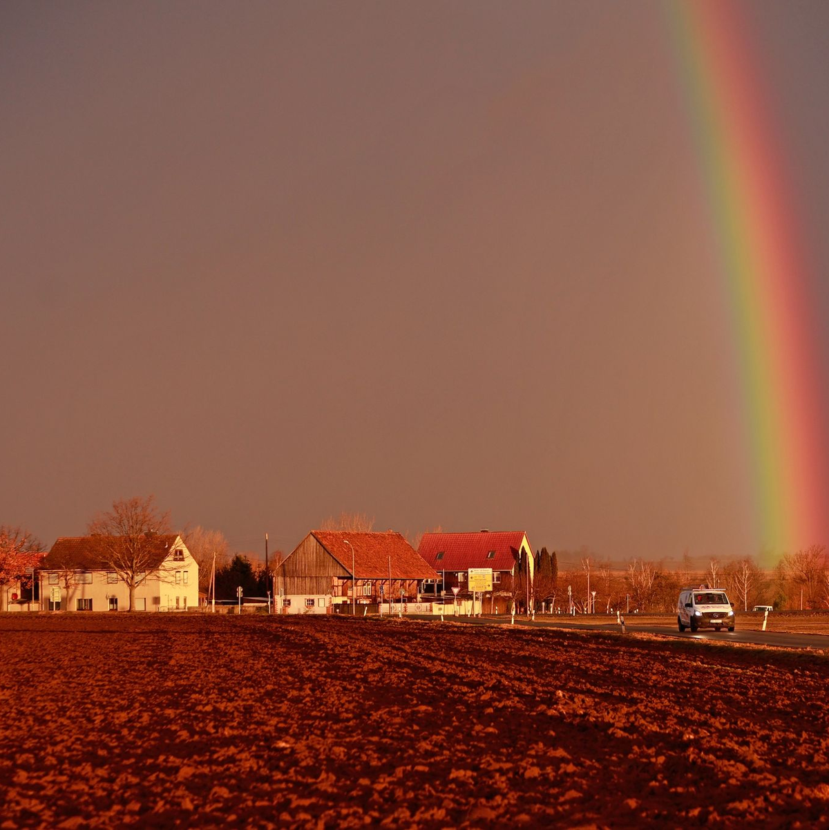 Ein Sturmtief kündigt sich bei tief stehender Sonne mit starkem Wind an, während sich ein Regenbogen am Himmel gebildet hat. - Foto: Matthias Bein/dpa