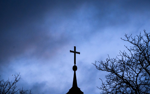 Dunkle Wolken über einem Kreuz einer Kirche: Einem der Missbrauchsopfer muss Schadenersatz gezahlt werden (Symbolbild). - Foto: Julian Stratenschulte/dpa
