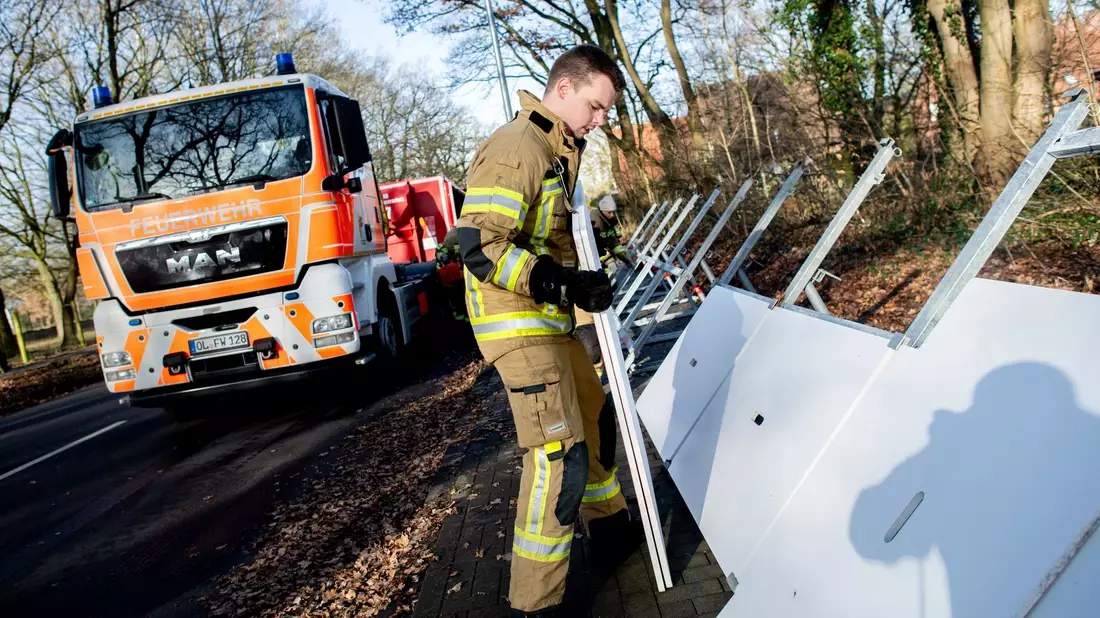Einsatzkräfte der Feuerwehr bauen ein mobiles Deichsystem ab. - Bild: Hauke-Christian Dittrich/dpa