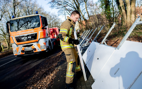Einsatzkräfte der Feuerwehr bauen ein mobiles Deichsystem ab. - Foto: Hauke-Christian Dittrich/dpa