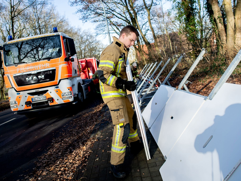 Einsatzkräfte der Feuerwehr bauen ein mobiles Deichsystem ab. - Foto: Hauke-Christian Dittrich/dpa