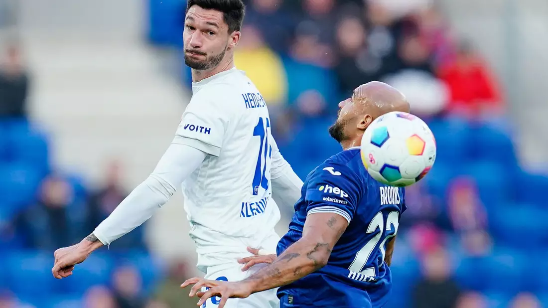 Heidenheims Tim Kleindienst (l) setzt sich im Kopfballduell gegen Hoffenheims John Anthony Brooks durch. - Bild: Uwe Anspach/dpa