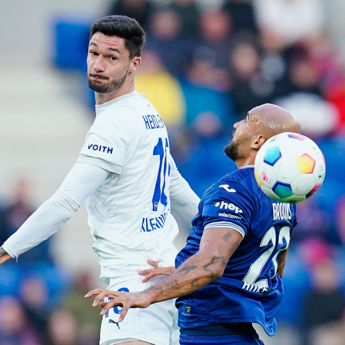 Heidenheims Tim Kleindienst (l) setzt sich im Kopfballduell gegen Hoffenheims John Anthony Brooks durch. - Foto: Uwe Anspach/dpa