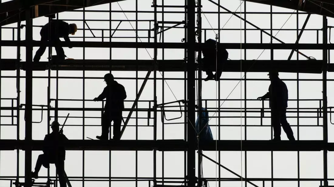 Arbeiter montieren auf einem Gerüst die Glasfassade des Bahnhofs von Frankfurt am Main. - Bild: picture alliance / dpa