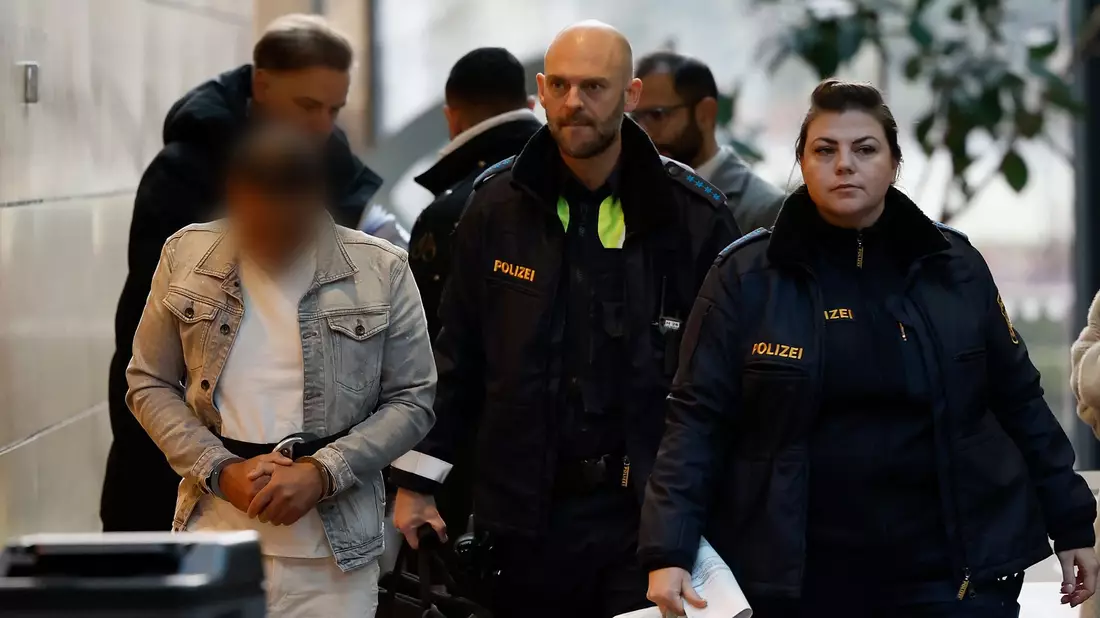 Der Angeklagte (l) wird in Handschellen zum Sitzungssaal im Landgericht Würzburg gebracht. - Bild: Heiko Becker/dpa