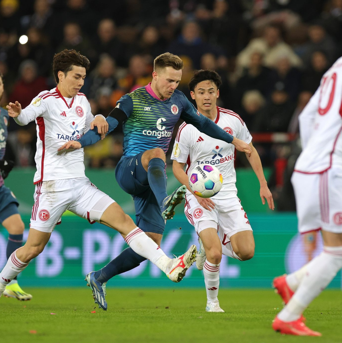 Johannes Eggestein (M) von St. Pauli setzt sich gegen Düsseldorfs Ao Tanaka (l) und Takashi Uchino (r) durch. - Foto: Christian Charisius/dpa