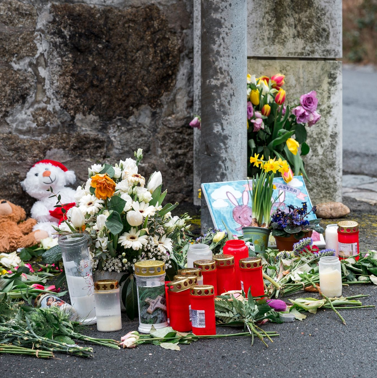 An einer Mauer vor dem Kinder- und Jugendheim in Wunsiedel, in dem eine Zehnjährige tot aufgefunden wurde, liegen Blumen, Kerzen und Stofftiere. - Foto: Daniel Vogl/dpa