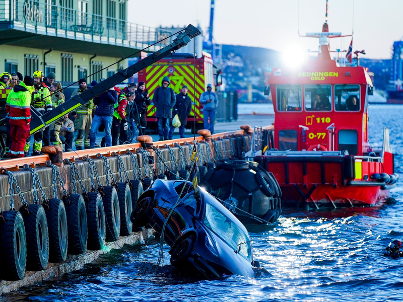 Feuerwehrleute bergen das versunkene Auto aus dem Fjord. - Foto: Håkon Mosvold Larsen/NTB/dpa