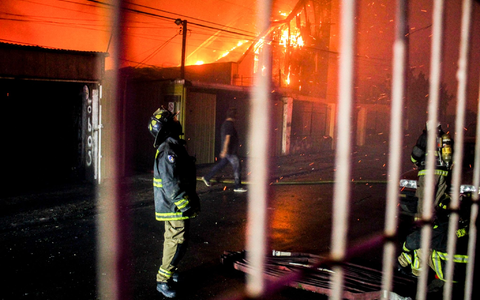 Ein Feuerwehrmann blickt nach oben, als die Flammen eines Waldbrandes auf Gebäude übergreifen. - Foto: Cristobal Basaure/AP