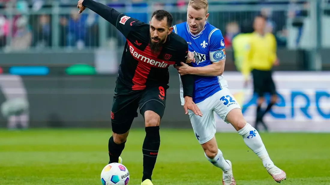 Darmstadt bemüht sich gegen Leverkusen: Fabian Holland (r.) im Duell gegen Leverkusens Borja Iglesias. - Bild: Uwe Anspach/dpa