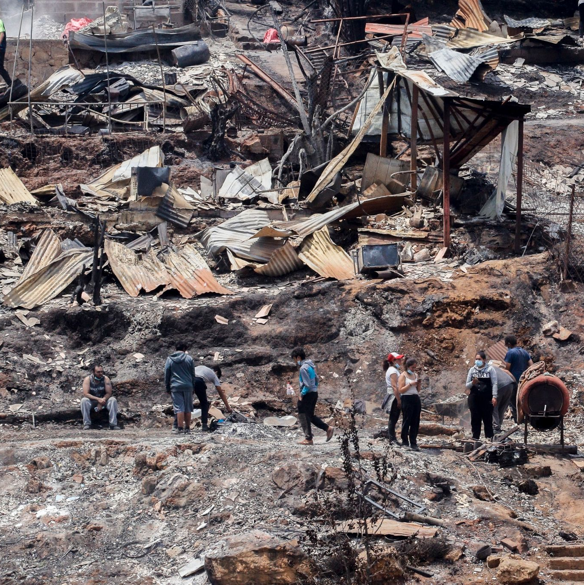 Einheimische arbeiten zwischen den Trümmern von ausgebrannten Häusern. - Foto: Cristobal Basaure/AP