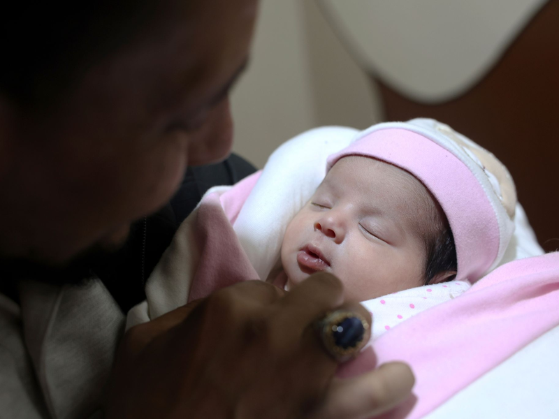 Adoptivvater Chalil Sawadi betrachtet Afraa wenige Tage nach ihrer Geburt. Das kleine Mädchen wurde unter Trümmern des Erdbebens in Syrien am 6. Februar 2023 geboren. - Foto: Ghaith Alsayed/AP/dpa