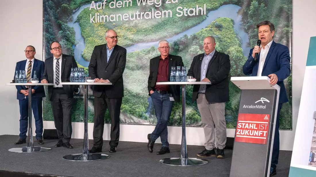 Wirtschaftsminister Robert Habeck (r) verkündet bei einer Betriebsversammlung die Förderzusage für den Umbau des Bremer Stahlwerks. - Bild: Sina Schuldt/dpa