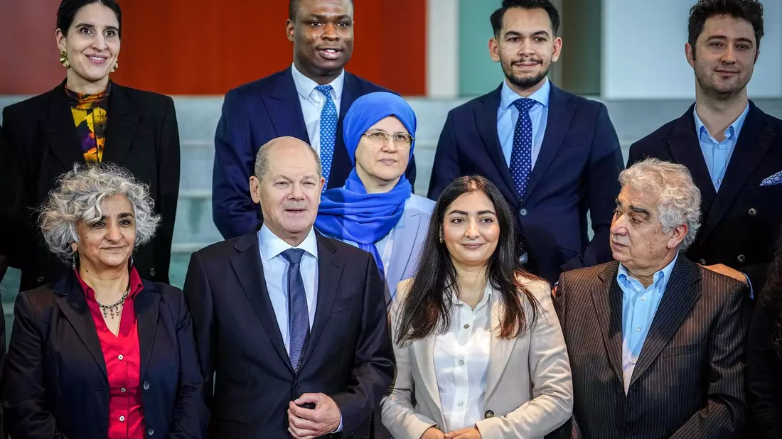 Olaf Scholz (erste Reihe, 2.v.l) und Reem Alabali-Radovan (2.v.r) nehmen am Treffen mit Vertreterinnen und Vertretern von Migrantenorganisationen sowie Netzwerken von Menschen mit Einwanderungsgeschichte teil. - Bild: Kay Nietfeld/dpa