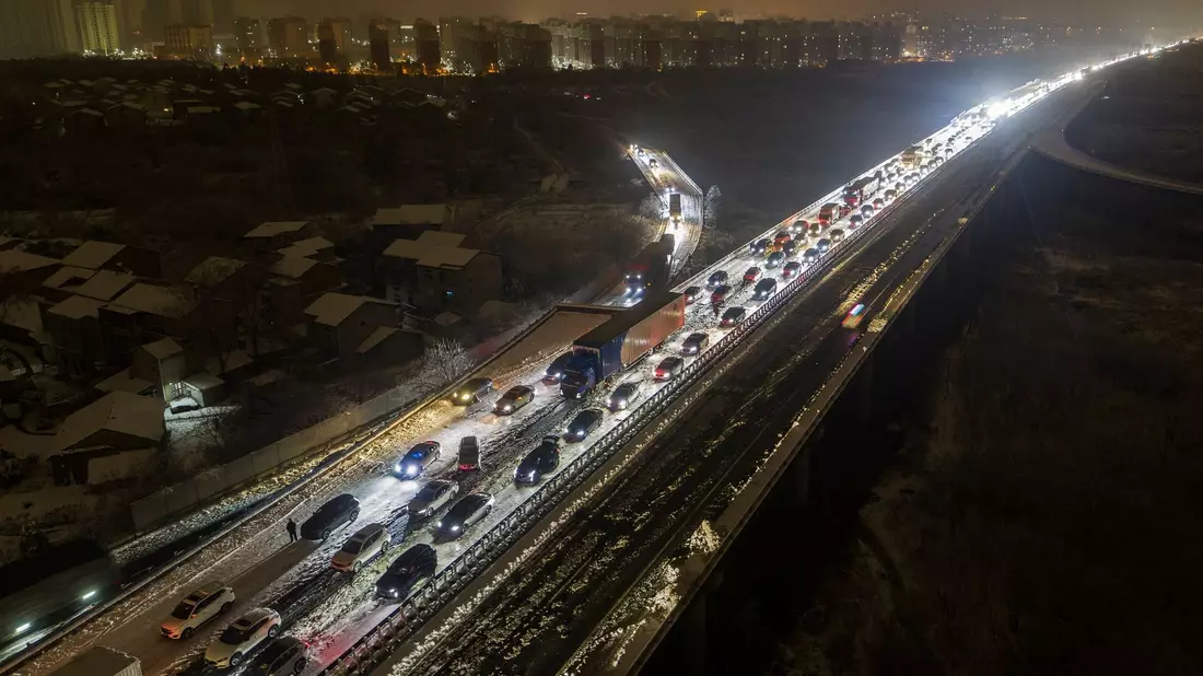 Fahrzeuge stecken auf einer Schnellstraße am Stadtrand von Wuhan fest: In Zentral- und Ostchina fiel viel Schnee. - Bild: Chinatopix/AP/dpa