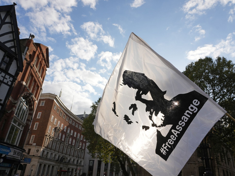 Eine Fahne mit dem Konterfei von Julian Assange wird bei einer Demonstration vor dem Royal Courts of Justice in London geschwenkt. - Foto: Jeff Moore/PA Wire/dpa