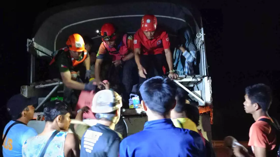 Rettungskräfte helfen Bewohnern des Dorfes Maco, sich nach dem Erdrutsch in Sicherheit zu bringen. - Bild: Uncredited/PHILIPPINE RED CROSS/AP/dpa